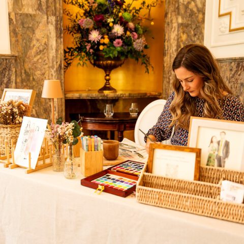 Artista pintando en acuarela en directo durante boda en el Hotel Ritz de Madrid con materiales profesionales y entorno elegante