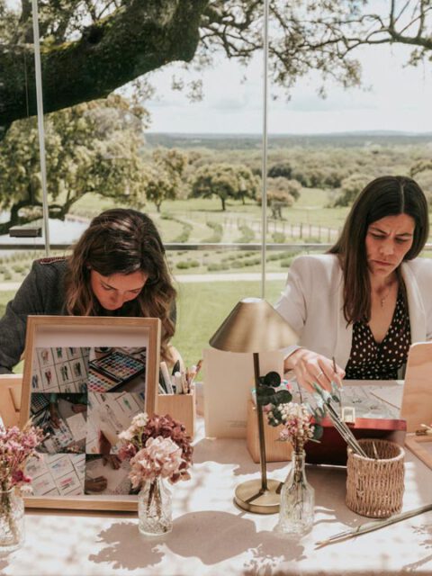 Artistas pintando en directo una acuarela a mano durante una boda al aire libre con decoración floral y entorno ajardinado