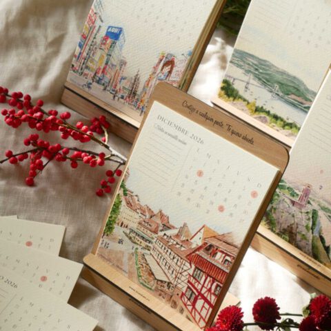 Página de diciembre del calendario ilustrado 2026 con acuarela de tejados de ciudad europea sobre soporte de madera natural