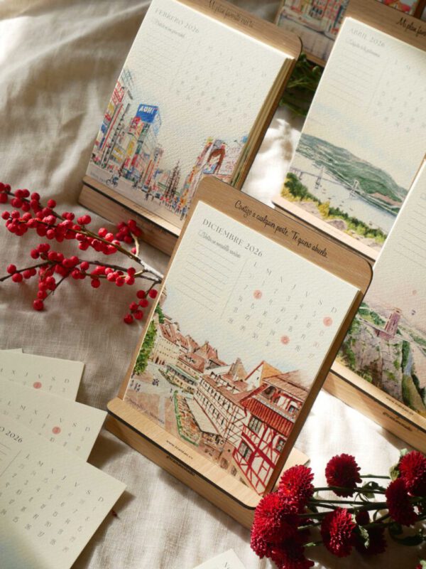 Página de diciembre del calendario ilustrado 2026 con acuarela de tejados de ciudad europea sobre soporte de madera natural