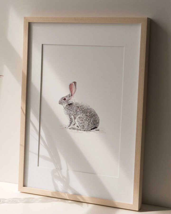 Ilustración artística de conejo pintado en acuarela sobre fondo neutro enmarcada en marco de madera natural para decoración infantil