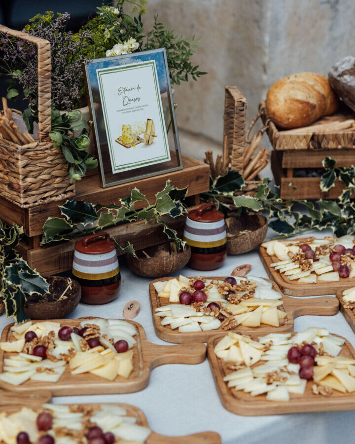 Cartel ilustrado de estación de quesos con acuarela artesanal enmarcado sobre mesa de degustación con quesos uvas y pan