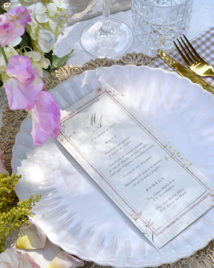 Minuta de boda coleccion Brisa sobre mesa decorada con flores lilas y servilleta a cuadros en escena lifestyle elegante