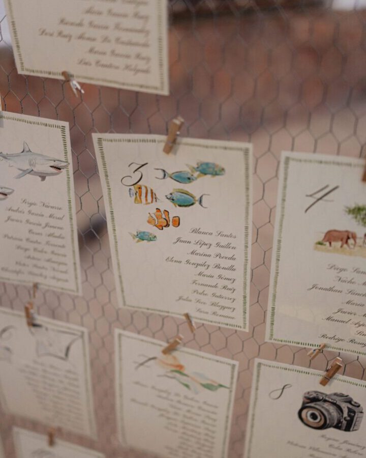 Seating plan de boda con tarjetas decoradas con acuarelas de animales de safari pintadas a mano y listas de invitados por mesas