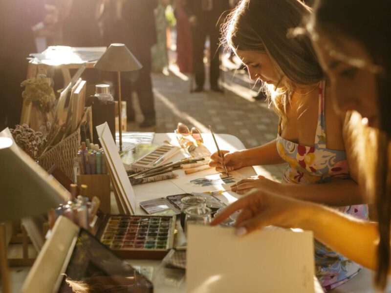 Artista especializada en live painting pintando una acuarela a mano en directo durante un evento al aire libre con luz natural