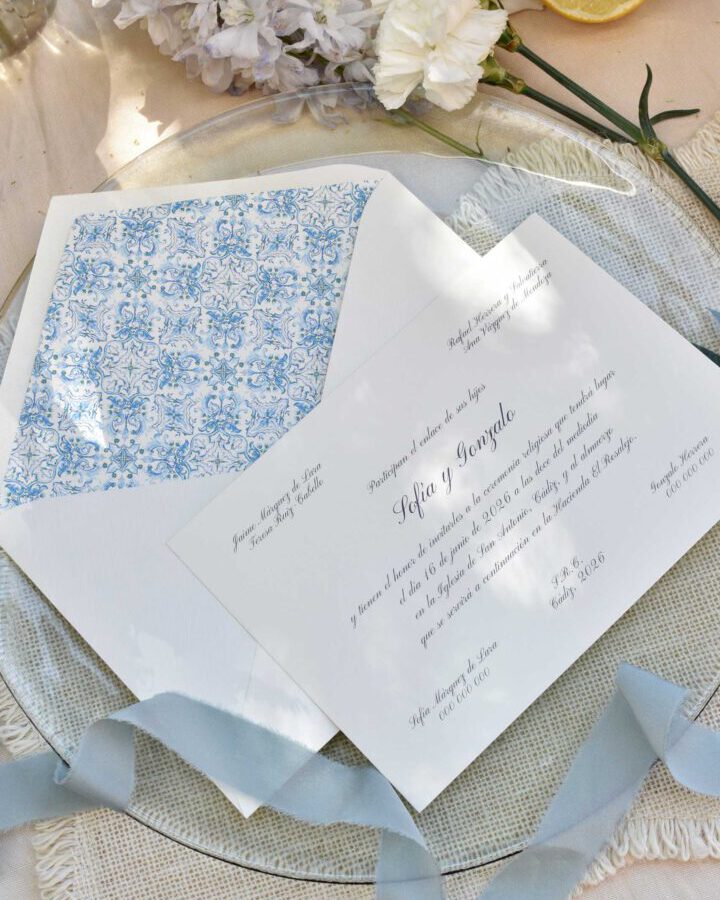 Invitación de boda con tipografía caligráfica sobre papel premium y sobre con forro interior de azulejos mediterráneos en tonos azules
