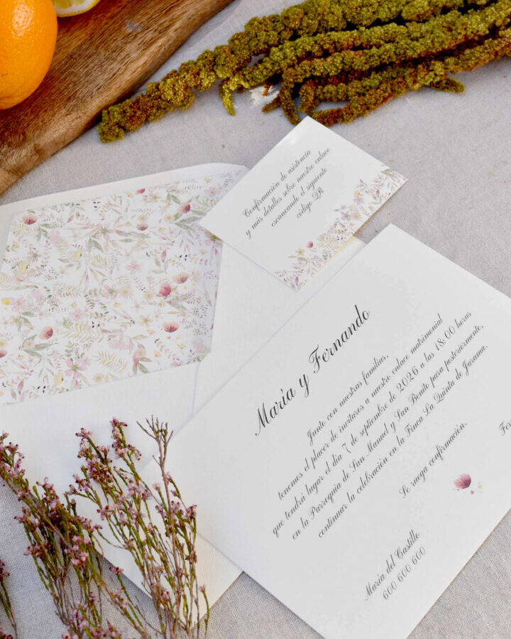 Composición lifestyle de la colección Sabrina mostrando invitación y sobre con forro floral en escena natural con flores secas