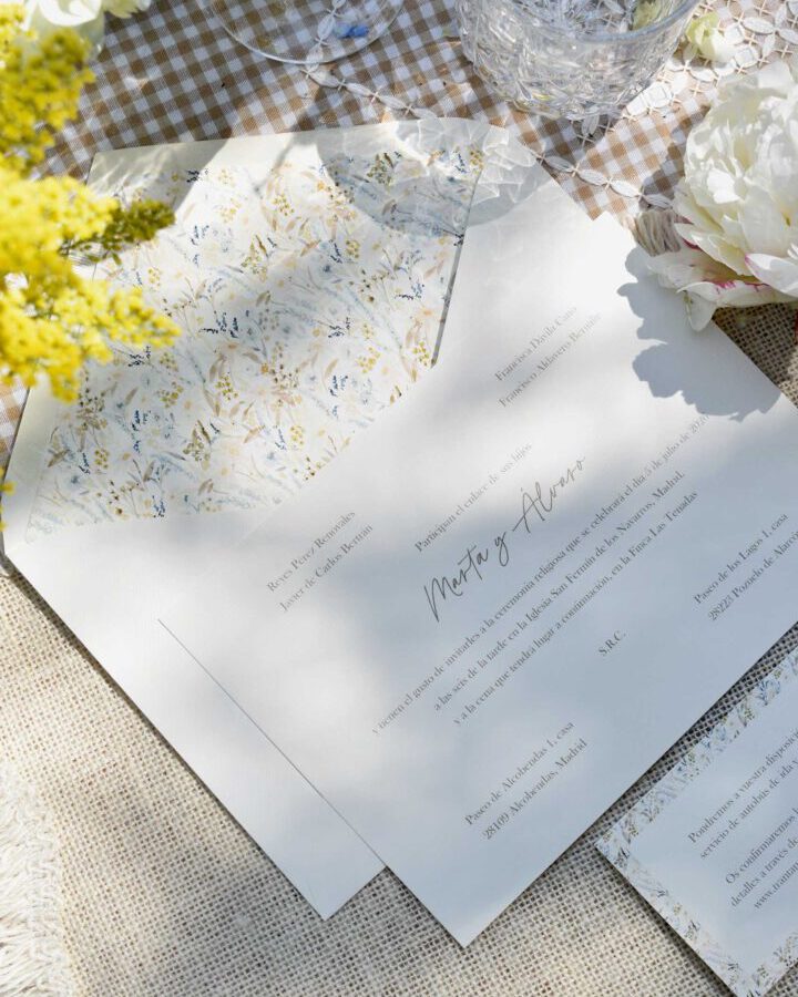 Conjunto de papelería de boda Margarot con invitaciones y tarjetas coordinadas presentadas en composición flat lay sobre fondo rústico con flores