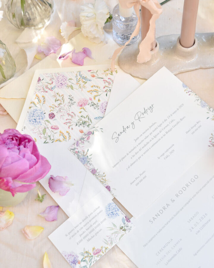 Conjunto de papelería nupcial colección Florecer con invitaciones decoradas con flores silvestres acuareladas presentadas en ambientación romántica