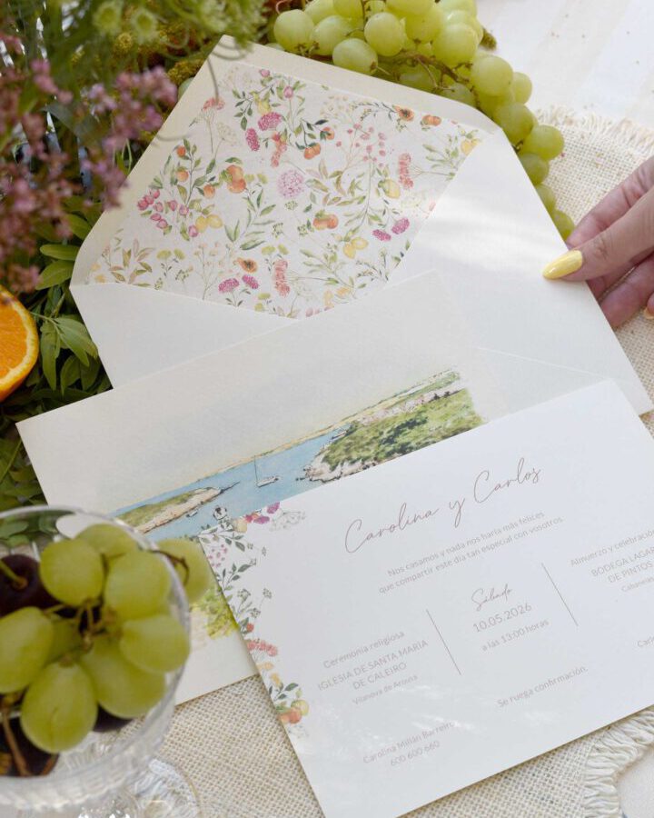 Detalle de invitación de boda Frutas de Trantán con sobre artesanal, ilustraciones frutales pintadas a mano y elementos decorativos naturales sobre textil rústico