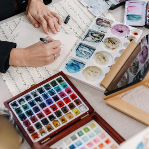 Artista de acuarela pintando en directo ilustraciones personalizadas durante una boda con paleta de colores y pinceles profesionales
