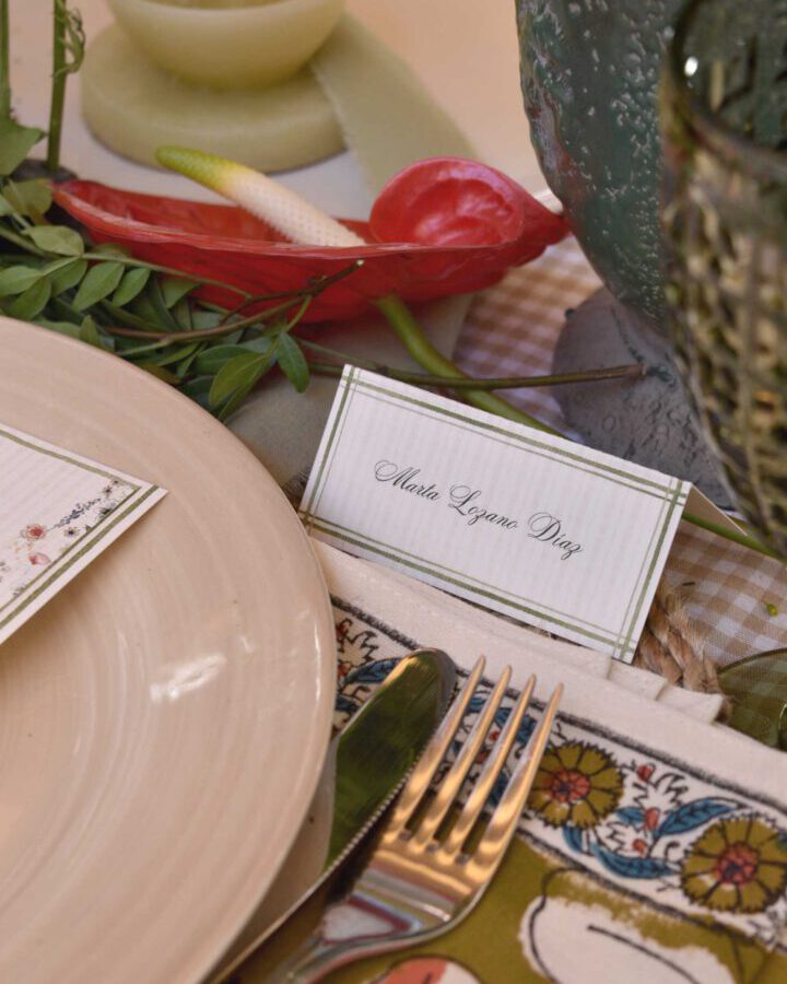 Marcasitio díptico con diseño de cuadros colocado junto al servicio de mesa en una boda con nombre caligráfico del invitado