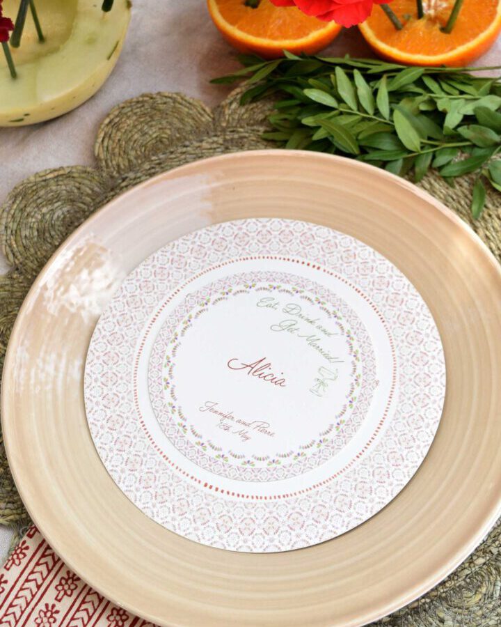 Marcasitio circular para boda con motivo de azulejo decorativo, nombre de invitado en caligrafía y orla geométrica sobre plato