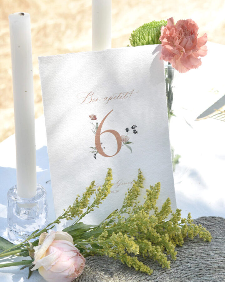 Mesero de boda Artesana con número de mesa ornamentado con ramas y hojas pintadas a mano en acuarela sobre estilismo rústico con vela y flores