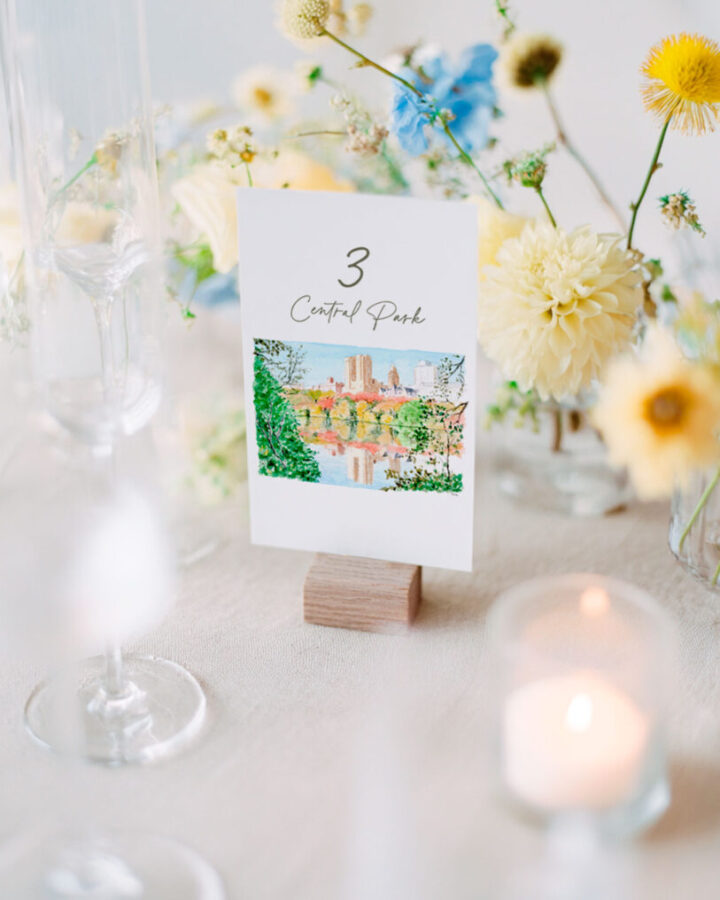 Mesero para boda con número de mesa e ilustración artesanal de Central Park Nueva York pintado en acuarela ambientado con flores amarillas velas y cristalería elegante