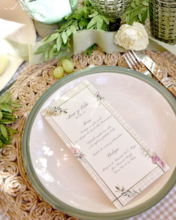 Minuta de boda personalizada con nombres Ana y Edu decorada con flores en acuarela y borde a cuadros sobre plato elegante