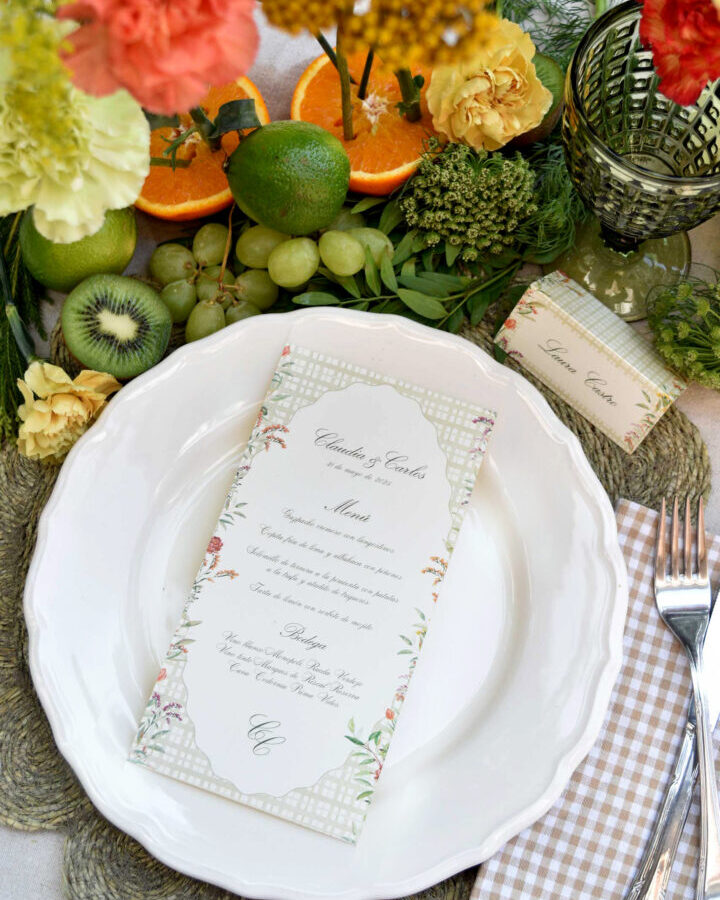 Minuta de boda con flores otoñales en acuarela presentada sobre plato cerámico en mesa campestre con flores y frutas
