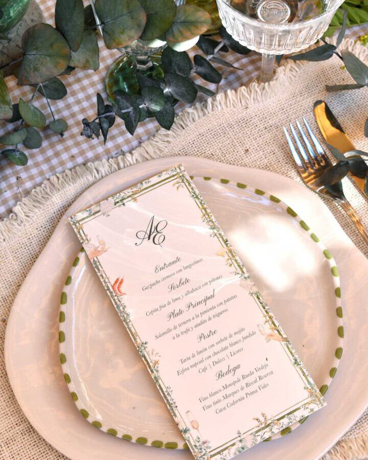 Minuta de boda con diseño de hojas y ramas de bosque pintadas a mano en acuarela y monograma sobre plato elegante