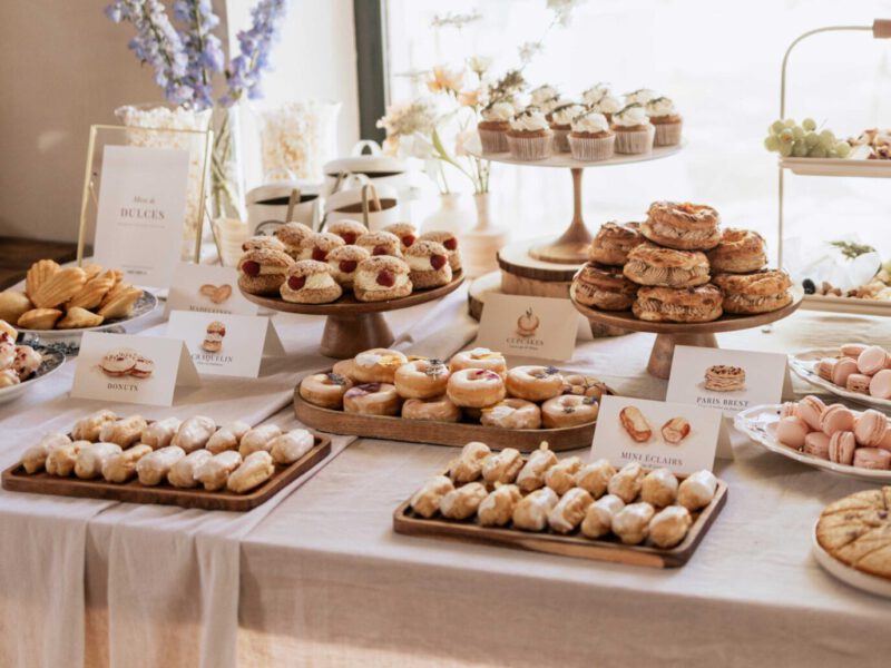 Mesa dulce o sweet table de boda con bandejas de dulces artesanales y carteles con lettering a mano identificando cada variedad