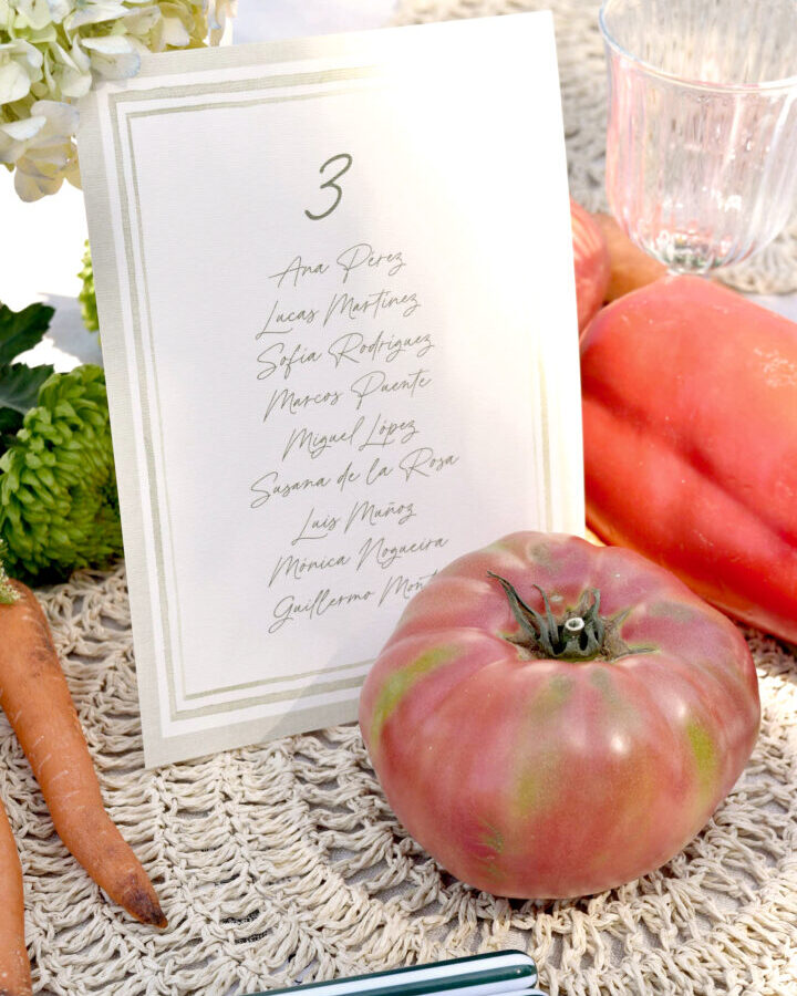 Tarjeta de seating plan modelo Ilustrada con marco decorativo minimalista y tipografía caligráfica presentada en ambiente nupcial elegante