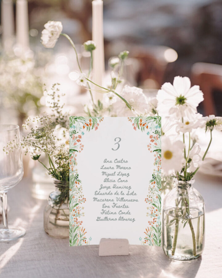 Tarjeta de seating plan modelo Bloom con flores silvestres y margaritas pintadas en acuarela a mano sobre papel premium en ambiente nupcial