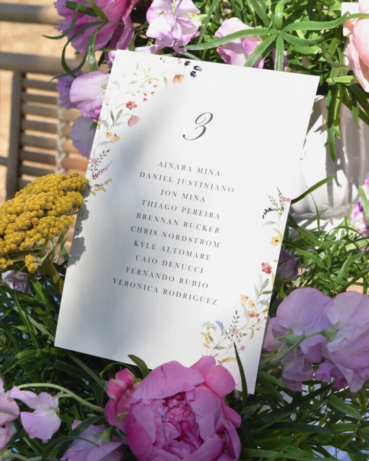 Tarjeta de seating plan modelo Frida con flores silvestres y hojas pintadas en acuarela a mano sobre papel premium con lista de invitados