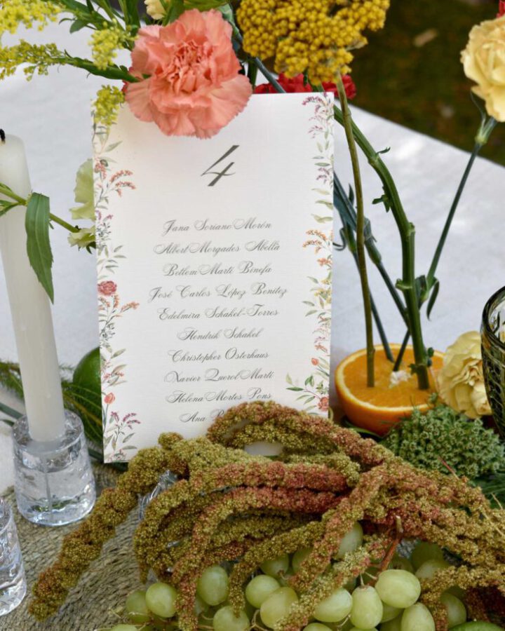 Seating plan de boda pintado a mano con tipografía caligráfica elegante y decoración floral otoñal sobre caballete de madera