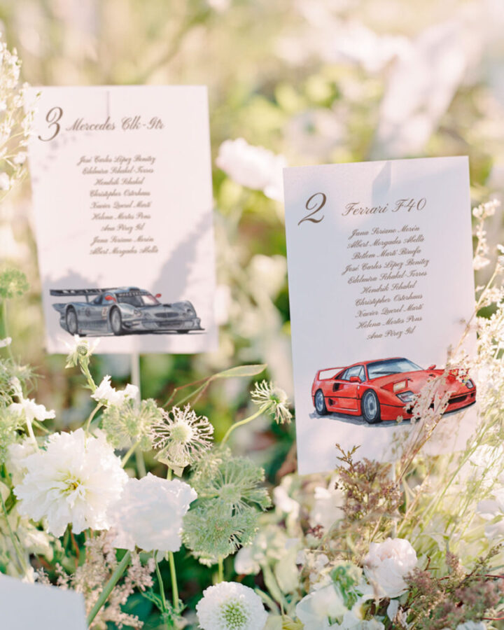 Tarjetas de seating plan para boda con ilustraciones de coches clásicos como Mercedes y Ferrari con listado de invitados en caligrafía